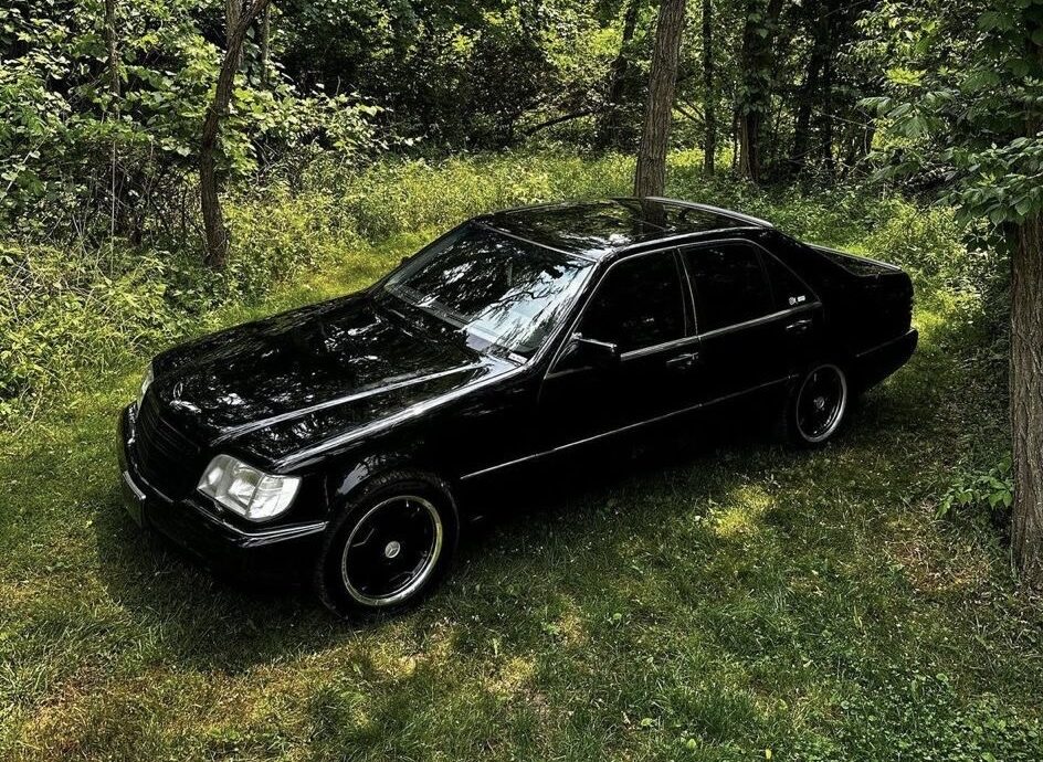 Gloss black sedan detailed by RT Auto Spa, parked in a wooded area
